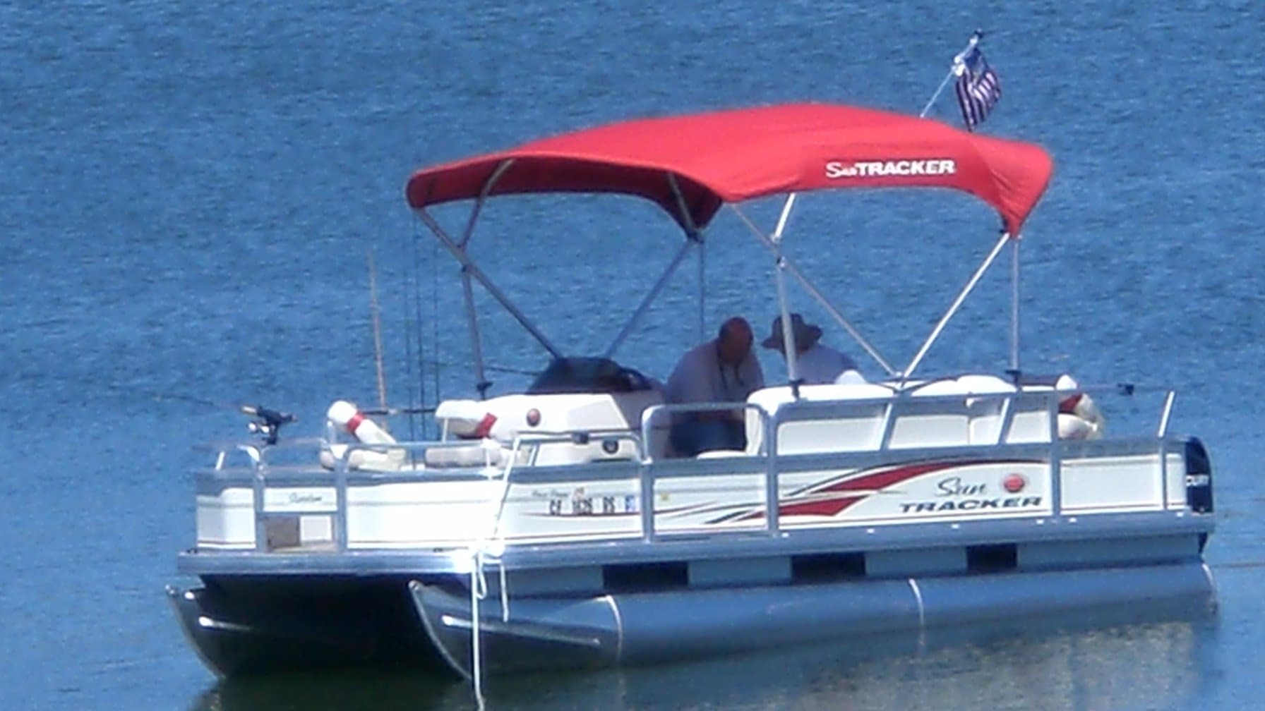 Bennington vs Barletta: a pontoon boat moored on calm water under a red bimini top